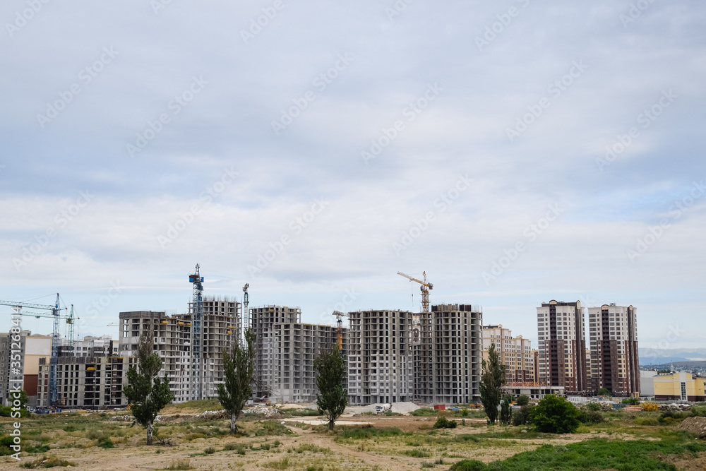 construction of multi-storey residential buildings. Tower cranes at a construction site.