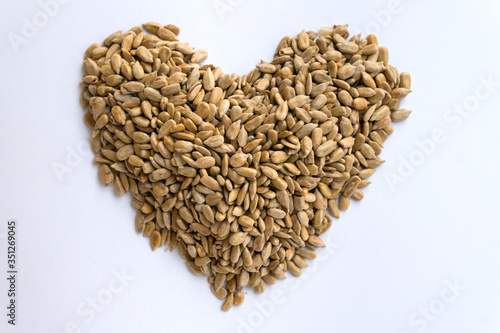 peeled sunflower seeds make a heart shape on white background