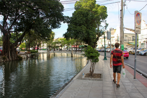 Bangkok canal with trees and person walking next door