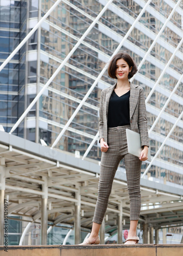 Businesswoman smiling in city and building in background.