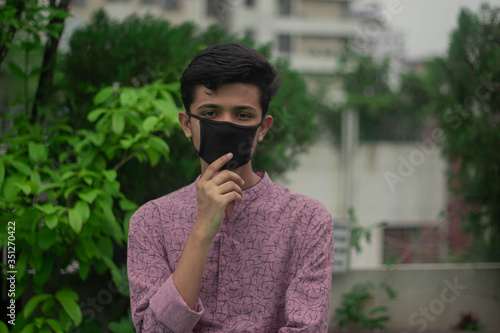 Muslim boy with traditional punjabi wears protective mask and celebrating ramadan eid ul fitor while staying at home due to the outbreak of pandemic coronavirus covid19