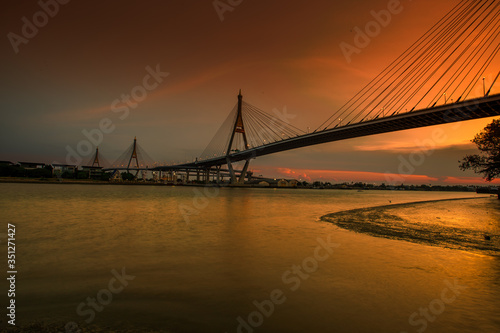 The blurred background of the twilight evening by the river, the natural color changes, the bridge over the river (Bhumibol Bridge) is one of the major transportation bridges in Bangkok, Thailand