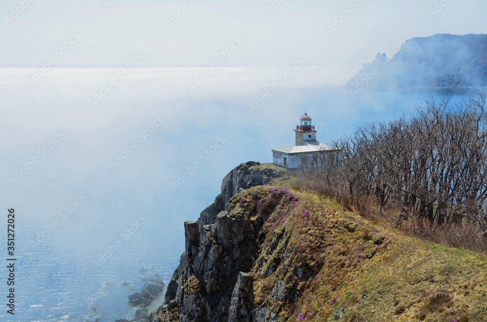 old lighthouse on a high sea shore in the fog