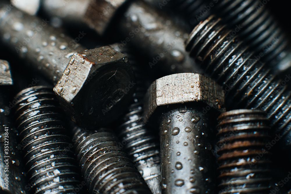 Bolts in oil close-up, macro. Drops of water on the metal. Carving on bots Bolts in oil close-up, macro. Drops of water on the metal. Carving on bots