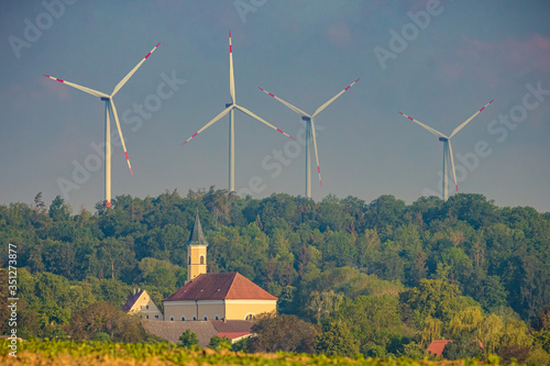 Church of St. Martin in Zöschingen, Bavaria, Germany. Small village on the border to Baden-Württemberg. Blue sky, sunny summer day. Wind turbines in the background
