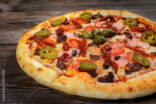 Pizza with jalapeno pepper, capers, bacon and pepperoni