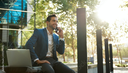 Smiling businessman talking on a cellphone outside his office building