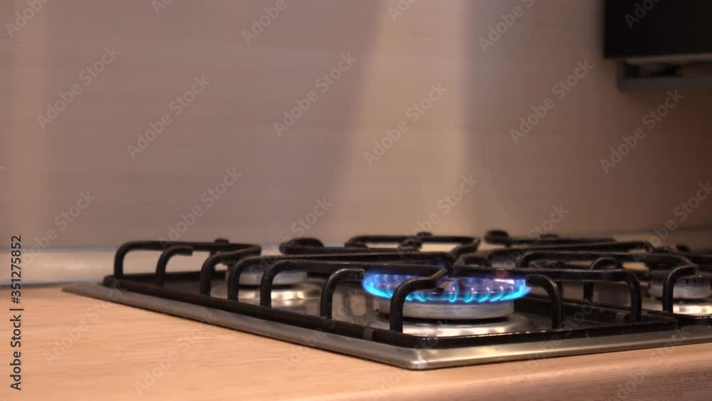 the hand ignites the gas comfort on the stove, the blue fire begins to