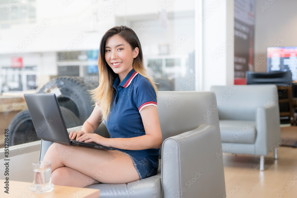 An Asian woman works while waiting for a car at the car service center. An Asian woman works while waiting for a car at the car service center.