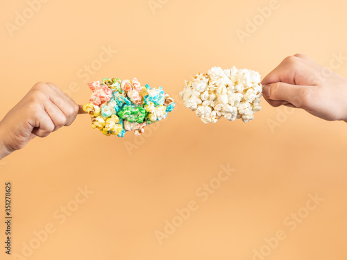 Hands holding two popcorn lollipops or ice creams, different composition