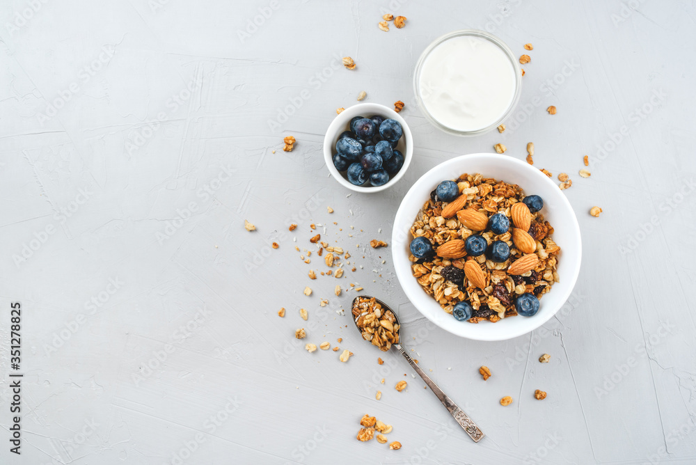 Baked granola with yogurt and blueberries on a gray table. Top view. Baked granola with yogurt and blueberries on a gray table. Top view.