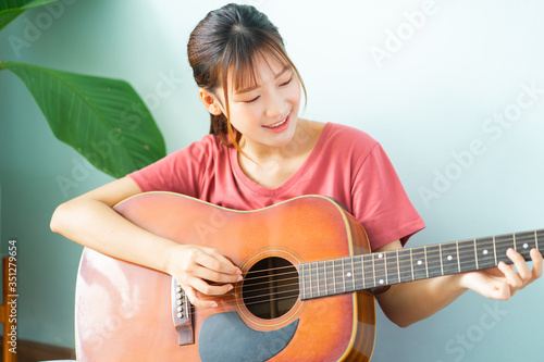 Young Asian woman learning guitar at home