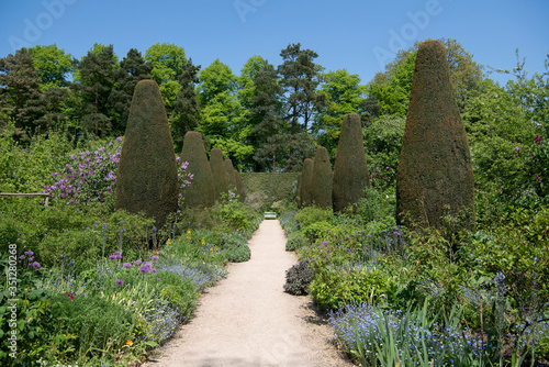 Path between herbaceous perennial borders of Pillar Garden, Hidcote, Gloucestershire, UK.