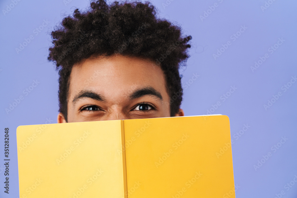 Photo of african american man covering his face with exercise book Photo of african american man covering his face with exercise book