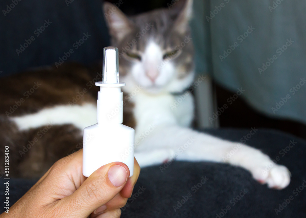 Man´s hand holding a bottle of nasal spray on the foreground and a