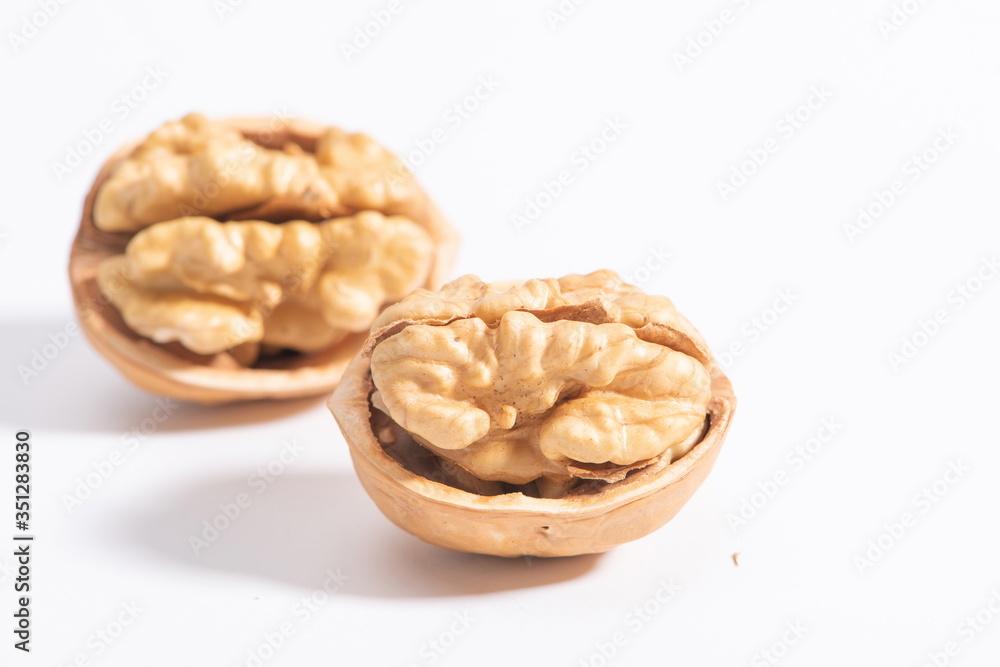 The walnuts poke open the shell to reveal the kernels in a white background The walnuts poke open the shell to reveal the kernels in a white background