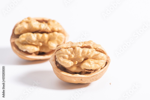 The walnuts poke open the shell to reveal the kernels in a white background
