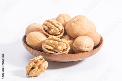 A few walnuts in a wooden bowl, isolated in a white background