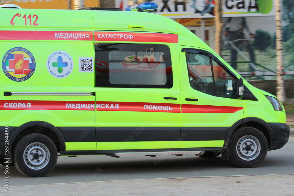 Fototapeta premium 14-05-2020. Russia, Syktyvkar. White ambulance with a red stripe with blue flashing lights on a city street in Russia.