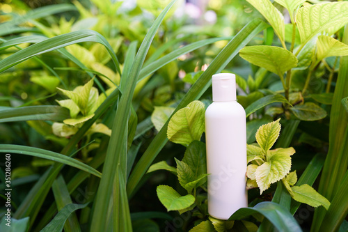 Clean body lotion bottle on green nature background.