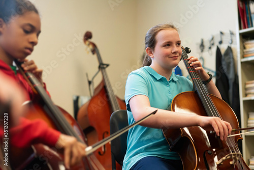 Teenage girls playing cellos in classroom