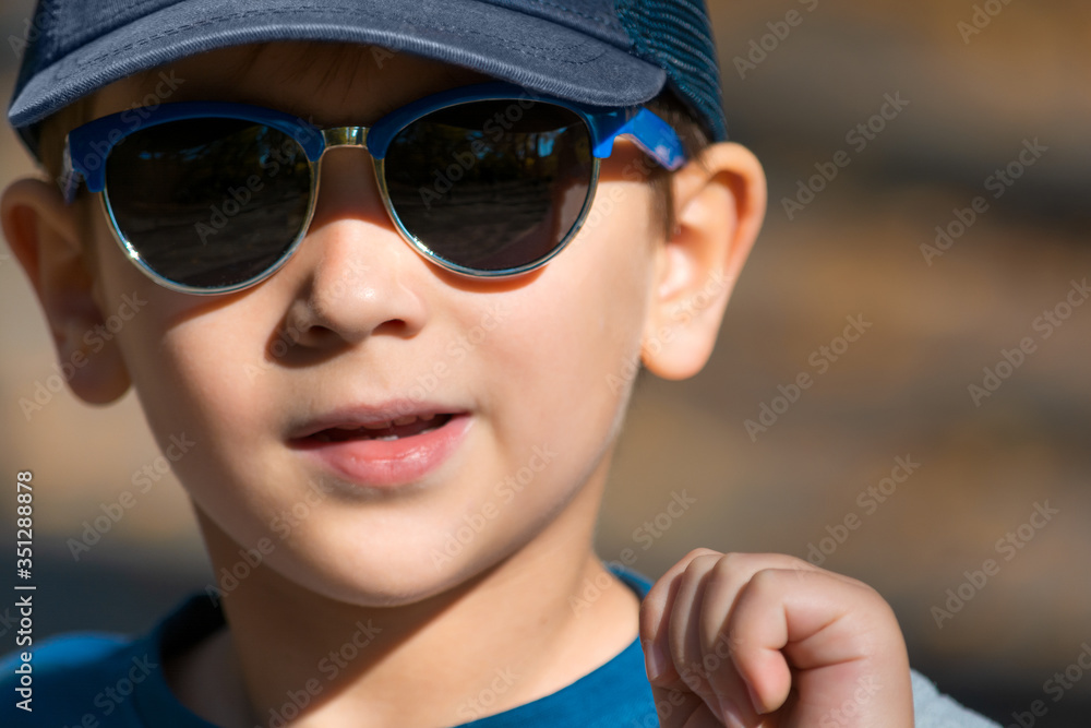Happy young boy wearing sunglasses running on outdoors. Autumnal park. Happy childhood concept Happy young boy wearing sunglasses running on outdoors. Autumnal park. Happy childhood concept