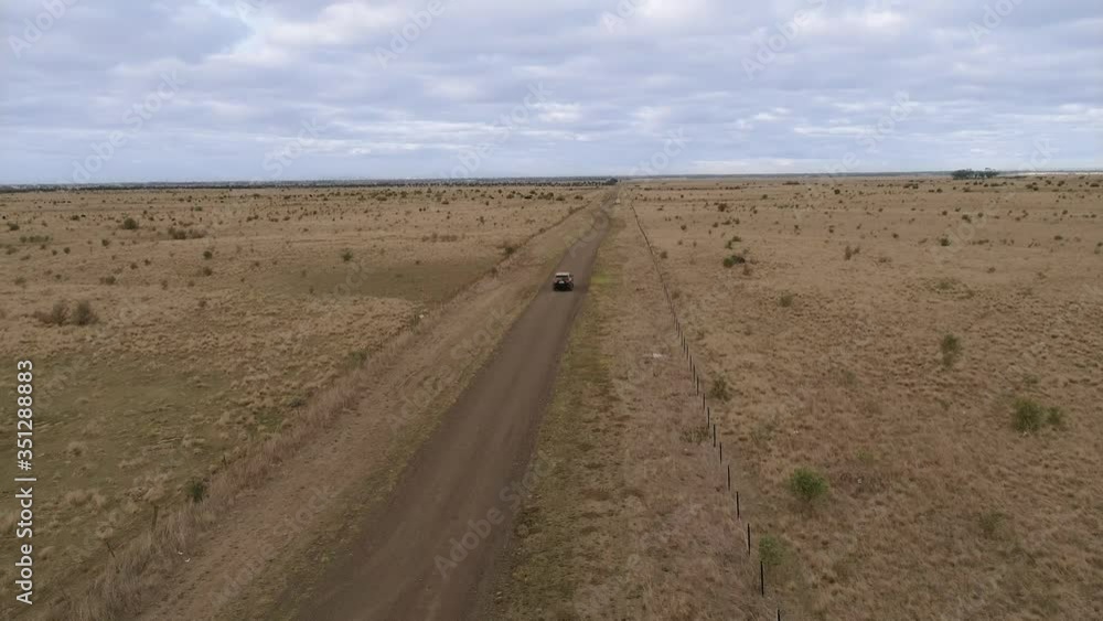 Aerial view of car driving on country road through blue sky Aerial view of car driving on country road through blue sky