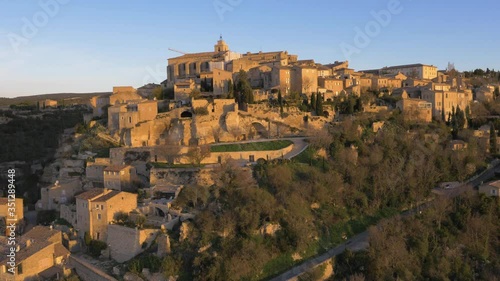 Houses built on steep rock faces in French town of Gordes. Aerial view at sunrise