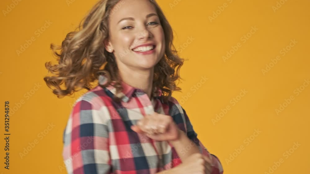 Young happy positive girl isolated over yellow wall background dancing Young happy positive girl isolated over yellow wall background dancing