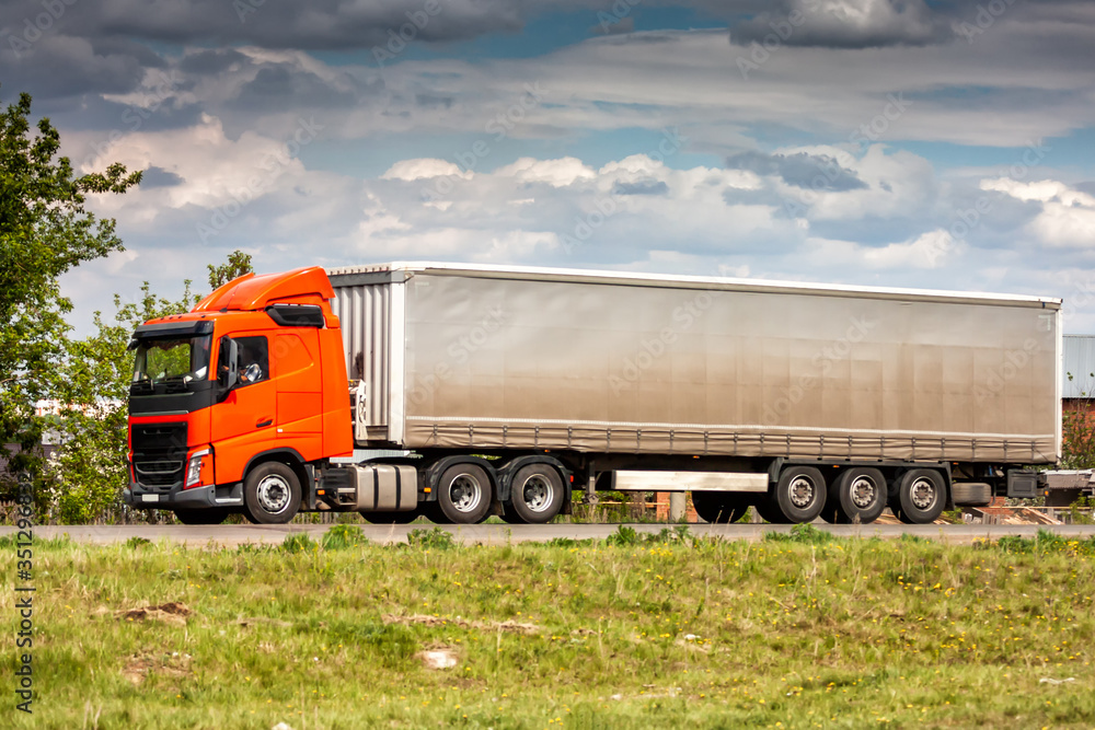 Long-distance truck with a semitrailer moves in the countryside