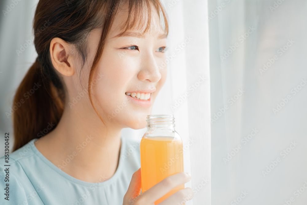 Young Asian woman drink orange juice beside the window at morning Young Asian woman drink orange juice beside the window at morning