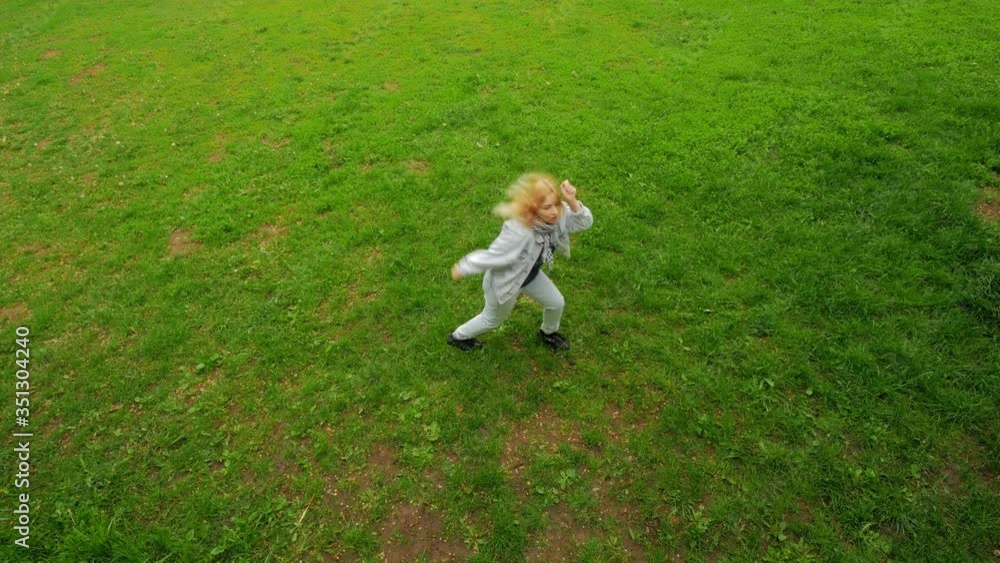 happy girl joyfully dancing on a green lawn