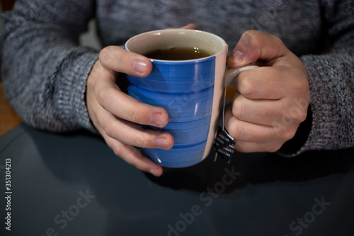 person holding a blue cup of tea