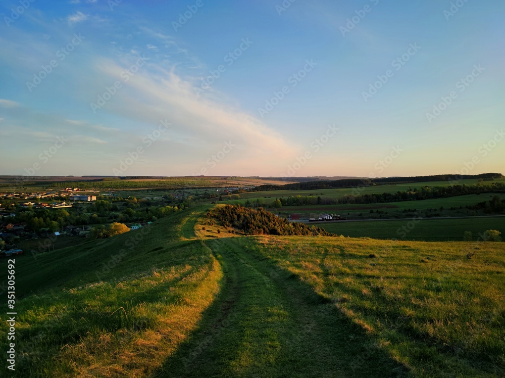 road among green grass on a hilltop near the countryside against a beautiful evening sky