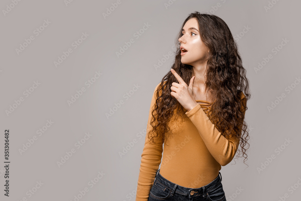 Look over there! Woman consultant in yellow on a white background shows a finger to the left with surprise and shock on her face. People expressive emotions concept Look over there! Woman consultant in yellow on a white background shows a finger to the left with surprise and shock on her face. People expressive emotions concept