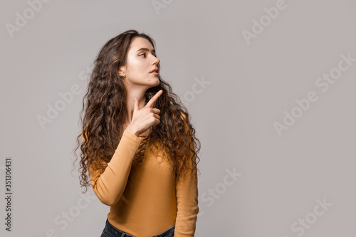 Look over there! Woman consultant in yellow on a white background shows a finger to the left. Copy space place for incept advertising, text or logo. People lifestyle concept. photo