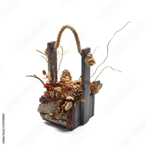 Wooden box filled with branches, dry leaves, orange berries, nuts and cones as a decorative composition