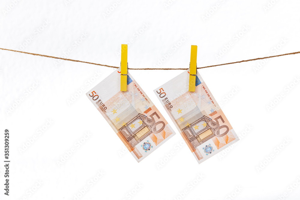 Euro banknotes are attached with yellow clothespins to a rope on a white background Euro banknotes are attached with yellow clothespins to a rope on a white background