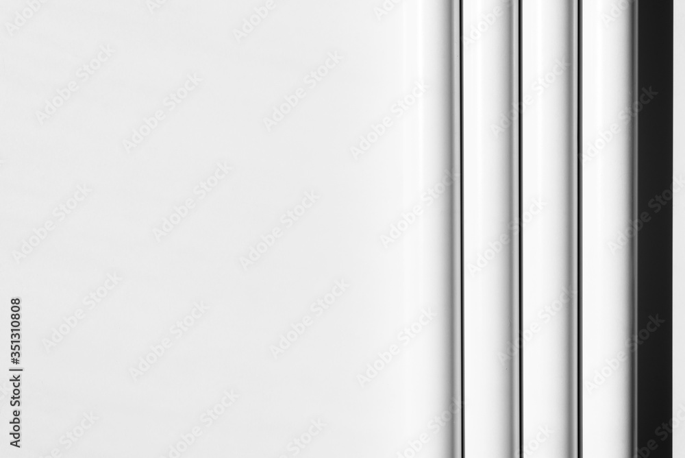 White tubes arranged in parallel, regular lines. Modern background. White, grey and black. Copy space. White tubes arranged in parallel, regular lines. Modern background. White, grey and black. Copy space.