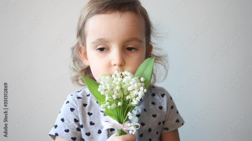Cute curly girl sniffs flowers lilies of the valley. Cute curly girl sniffs flowers lilies of the valley.