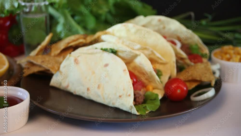 Man hand take a Mexican tacos with chicken meat, beans, tomatoes and corn. Man hand take a Mexican tacos with chicken meat, beans, tomatoes and corn.