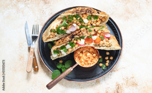 Healthy vegetarian tortilla or pita bread with chickpeas, vegetables and herbs served with homemade hummus in vintage dishes. Healthy eating concept. Light background. Top view. Copy space