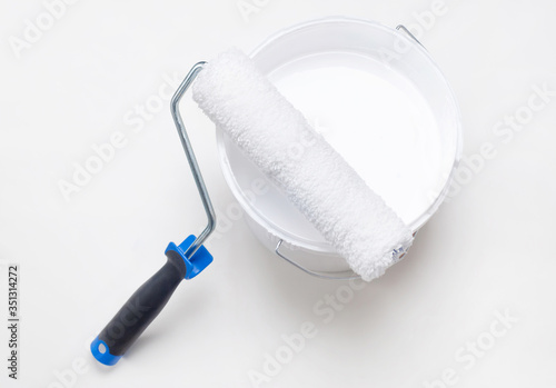 House repair, roller with a bucket of white paint