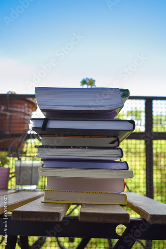 Books piled up and placed on a wooden table at home