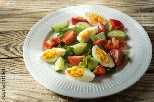 rustic summer salad with fresh cucumbers, tomatoes and eggs on a white plate