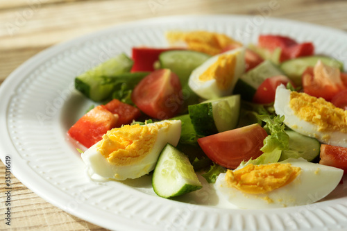 rustic summer salad with fresh cucumbers, tomatoes and eggs on a white plate