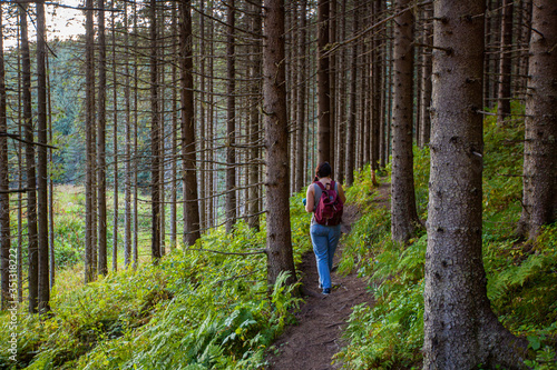 Traveler woman with red backpack walking in the forest