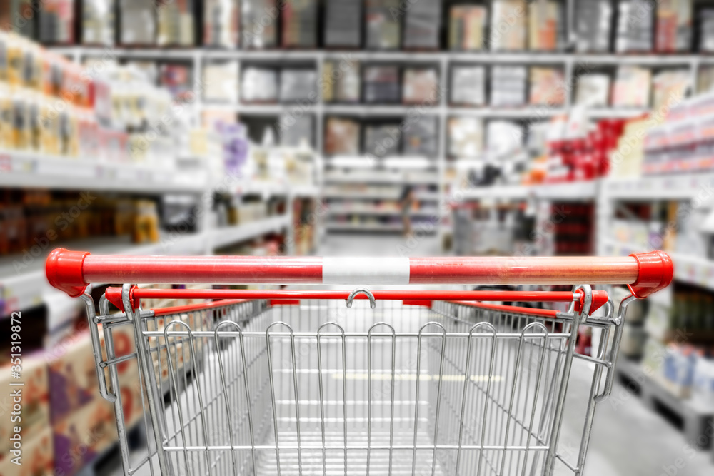 The empty red shopping cart in supermarket with blurred background. The empty red shopping cart in supermarket with blurred background.