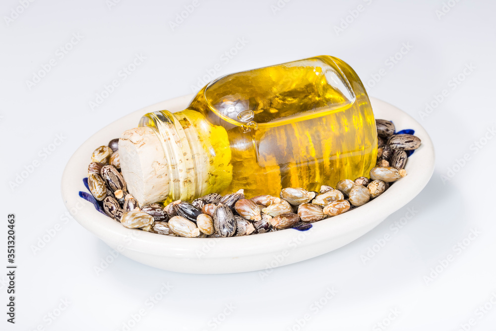 castor oil and grains in bowl isolated on white background castor oil and grains in bowl isolated on white background