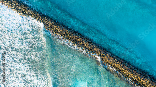Aerial view of waves breaking at the stone walls of the harbour entry of  the local / inhabited island Vashafaru, Haa Alif Atoll, Maldives, Indian Ocean photo